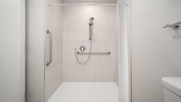 A modern shower area with a grab bar, a handheld showerhead, and a control panel.