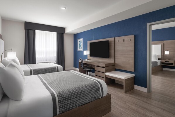 Una habitación de hotel moderna con dos camas, un escritorio, una silla, un televisor de pantalla plana y un espejo grande.