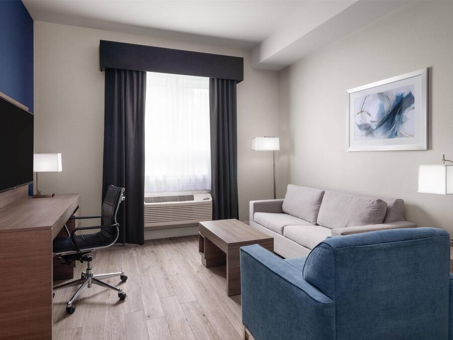 Habitación de hotel con escritorio, silla, sofá y dos lámparas de noche.