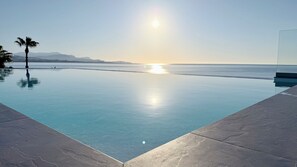 A clear view of an infinity pool with a sunset in the background, a palm tree, and a mountain range. - 3P - SANDY BEACH - A/C - swimming pool - Wifi (Villeneuve-Loubet)