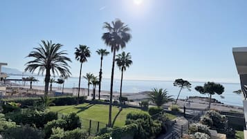 Blick auf einen Strand mit Palmen, einem klaren Himmel und einem fernen Gebirge.
