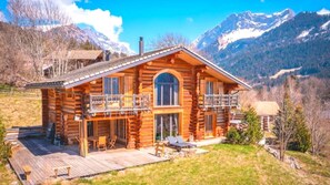 A log cabin with a balcony, a deck, and a mountain backdrop. - Chalet (Gryon)
