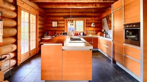 Una cocina de estilo cabaña de troncos con paredes de madera, una isla central y electrodomésticos modernos.