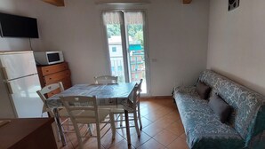 Una cocina compacta con una mesa de comedor, sillas, un sofá y un televisor montado en la pared.