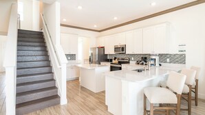 Une cuisine moderne avec des meubles blancs, un îlot central et un four à micro-ondes encastré.