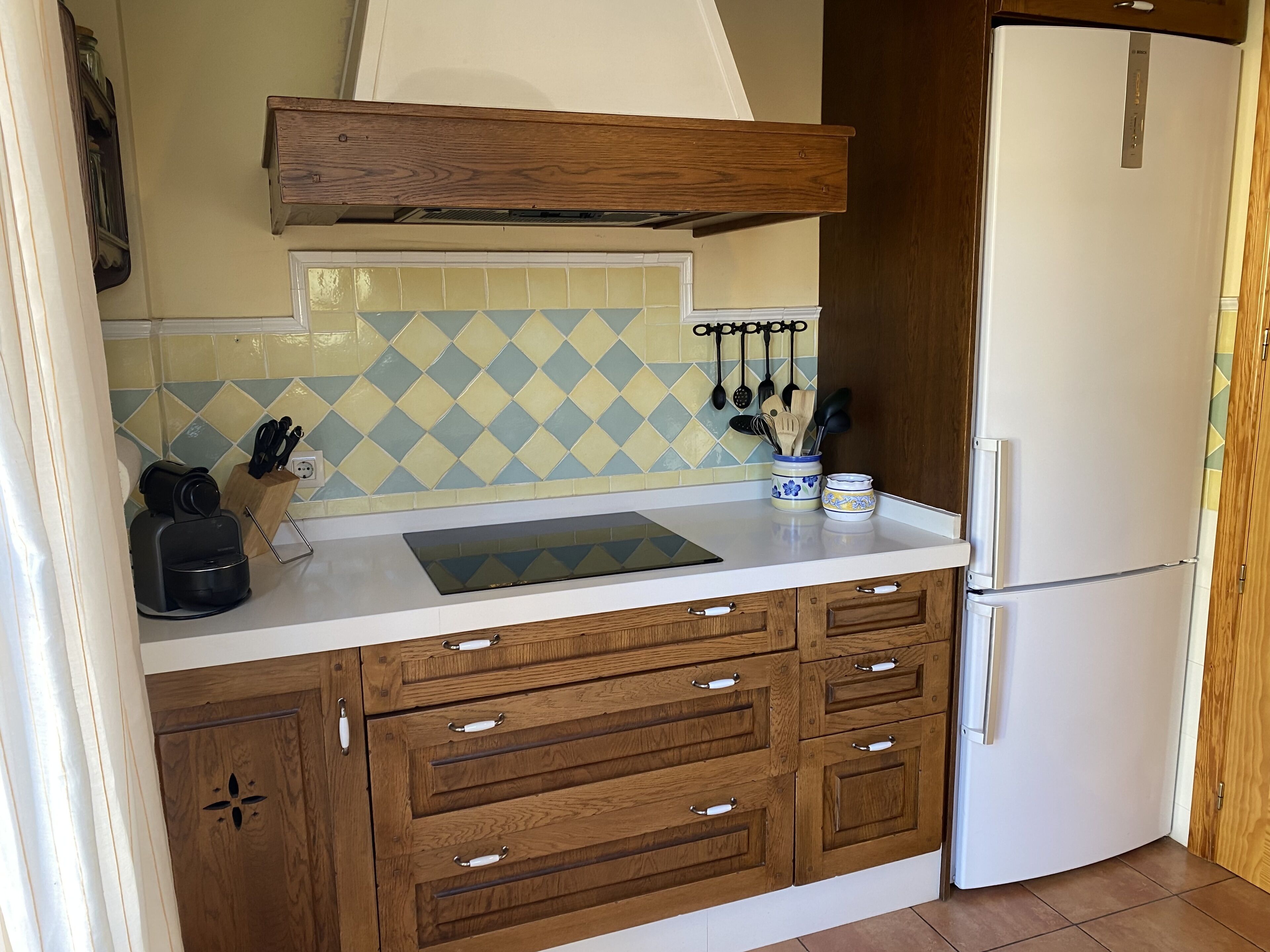 A kitchen with wooden cabinets, a white refrigerator, a coffee maker, and a tiled backsplash.