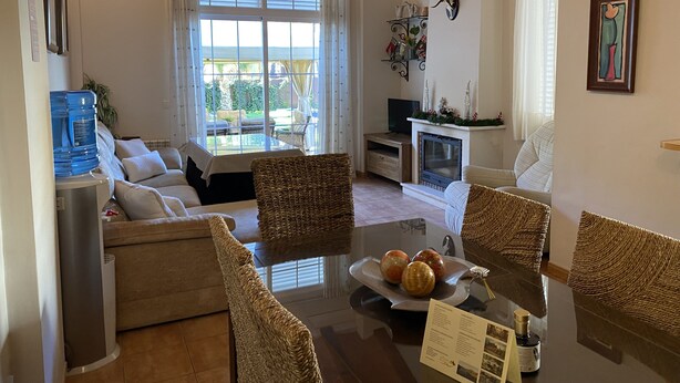 A cozy living room with a sofa, two wicker chairs, a glass coffee table with fruit, a fireplace, and a TV. - Casa el Paraíso del Lago Rural Lodging (AN)