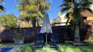 A backyard with artificial grass, a pool, two lounge chairs, and an umbrella. - Casa el Paraíso del Lago Rural Lodging (AN)