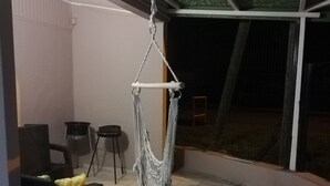 Eine Hängematte im Innenbereich, ein Stuhl mit Kissen und ein Fliesenboden.