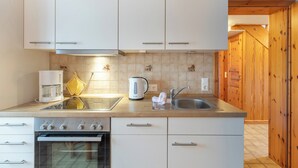 A modern kitchen with white cabinets, a stainless steel sink, and a built-in oven. - Guesthouse Am Badedeich, vacation apartment Sylt in Dagebüll for up to 4 people (Dagebüll)