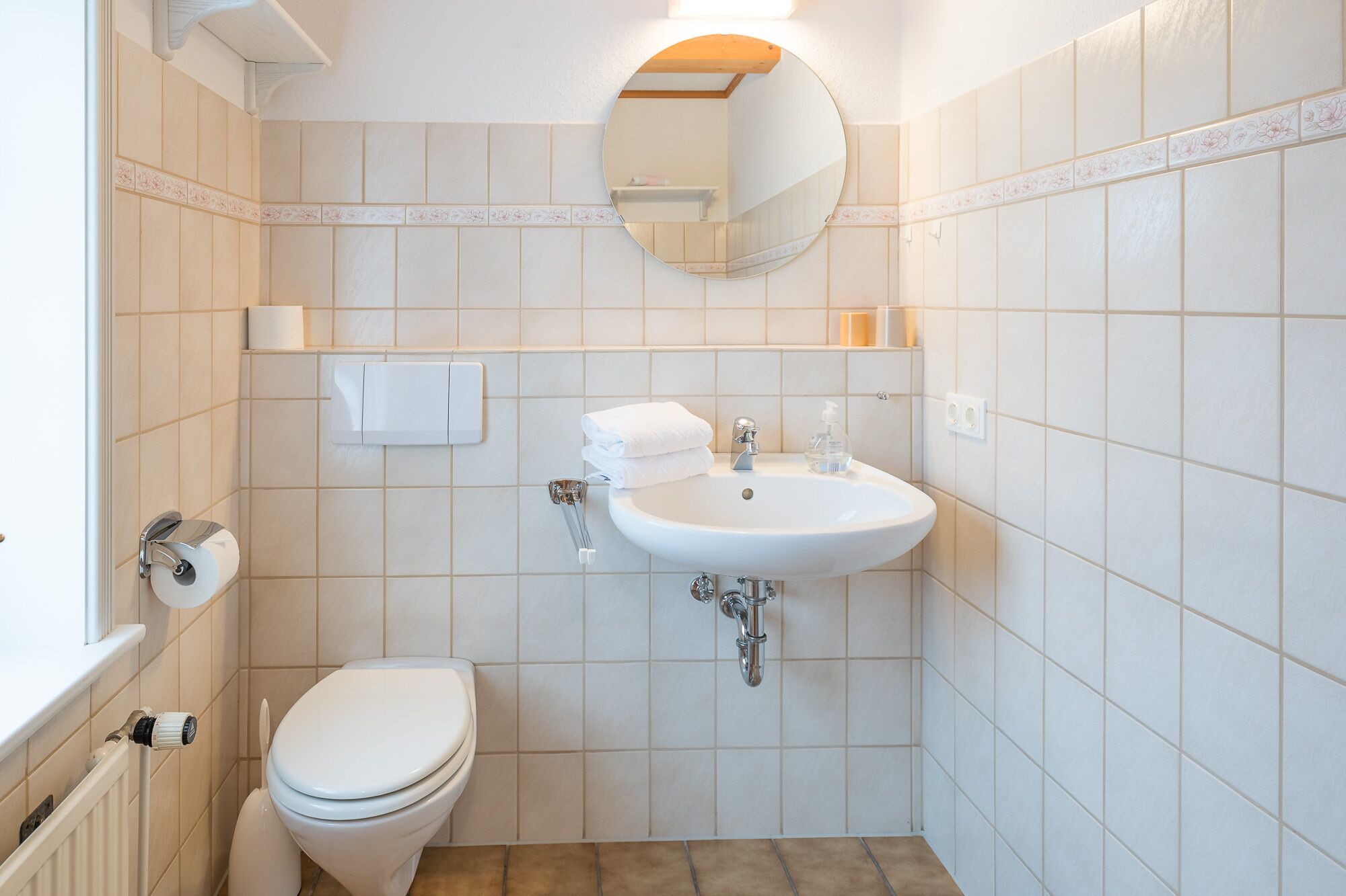 A bathroom with a toilet, sink, and mirror.