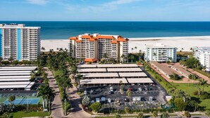 A coastal hotel complex with multiple buildings, a parking lot, and a beach view. - Beachfront 2BR/2BA condo with pool, WiFi, and coastal views. (Marco Island)