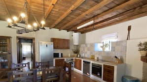 A spacious kitchen with wooden cabinets, a dining table, and a hanging light fixture.