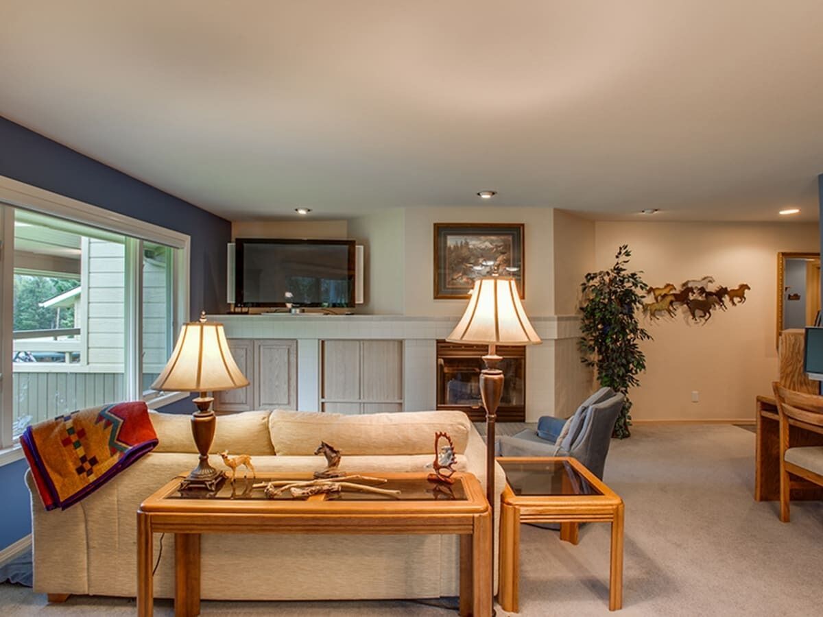 A living room with a sofa, two side tables with lamps, a television, and a fireplace.