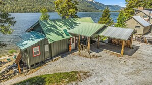 Een chalet met een groen dak, een veranda en uitzicht op een meer en bergen.