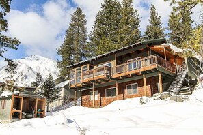 Eine Holzdiele mit Balkon, umgeben von Schnee und Bäumen.