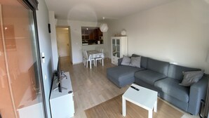 A modern living room with a grey sofa, a white coffee table, and a dining area with a table and chairs. - Private property in front of Boadella beach (Lloret de Mar)