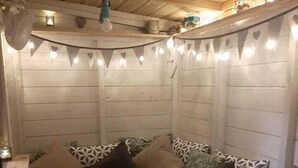 A cozy corner with a wooden bench and a cushioned seating area, adorned with heart-shaped lights. - Stunning Riverside Town House With Views, Ayrshire (Girvan)