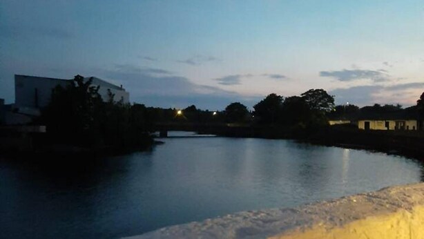Two lit lanterns on a wooden ledge overlooking a calm body of water at dusk. - Stunning Riverside Town House With Views, Ayrshire (Girvan)