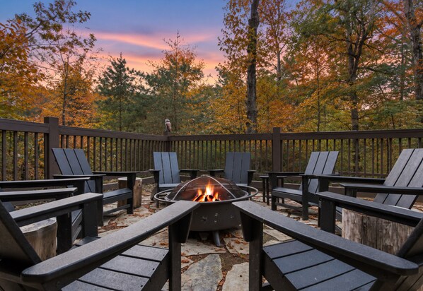 An outdoor seating area with a fire pit and Adirondack chairs.