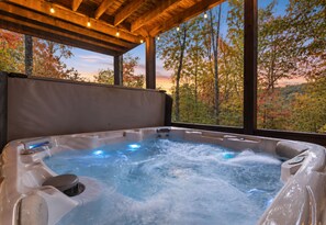 Un jacuzzi con techo de madera y amplios ventanales con vistas a un bosque.