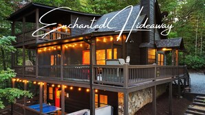 A two-story wooden cabin with a deck, string lights, and a ping pong table. - TreeHouse Vibe • Slide, Swings, Rock Wall • HotTub • FirePit • Games • Secluded (Blue Ridge)