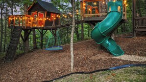A treehouse with a slide, surrounded by a forest. - TreeHouse Vibe • Slide, Swings, Rock Wall • HotTub • FirePit • Games • Secluded (Blue Ridge)