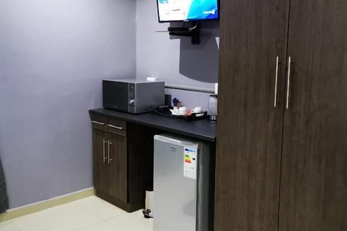Una kitchenette compacta con microondas, un refrigerador pequeño y un televisor de pantalla plana sobre la encimera.