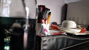 A coffee maker, a cup, a plate with food, and a bag of Nescafe Classic coffee packets on a table.