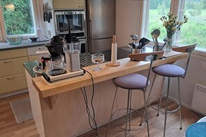 A modern kitchen with a bar area, stainless steel appliances, and a view of the garden.