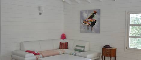 A white wooden room with a white sofa, a small wooden table, and a painting on the wall.