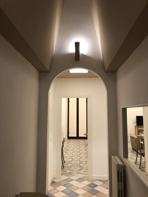 Un couloir doté d’un sol à motifs, d’une porte en arc de cercle et d’un radiateur.