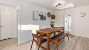 A dining area with a wooden table and chairs, a framed bull picture, a clock, and a ceiling light.