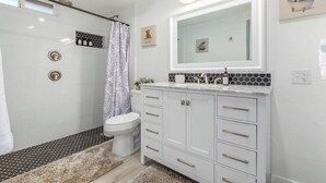 A modern bathroom with a shower, toilet, and vanity with a large mirror.