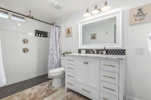Un bagno moderno con doccia, toilette e lavabo con uno specchio grande.