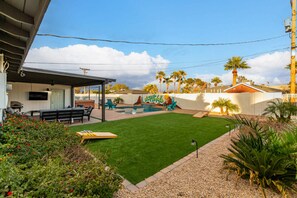 Un jardin avec une piscine, des meubles de patio et un espace salon abrité.