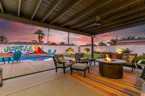 Une terrasse extérieure avec une piscine, des chaises, un foyer et une fresque murale.