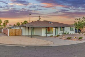 A single-story house with a sloped roof, a fenced yard, and a driveway.