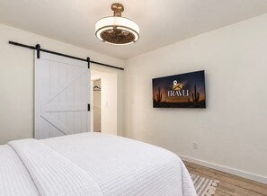 A bedroom with a bed, a sliding door, a ceiling fan, and a wall-mounted artwork. - The Eldorado | Two Masters | Pool + Hottub | Mural (Scottsdale)