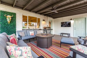 A cozy living room with a fireplace, a sofa set, a TV, and a green wall with a bull decoration.