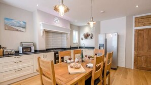 A modern kitchen with white cabinets, a wooden dining table, and a stainless steel refrigerator. - 4 Market Cross House, Aldeburgh (Aldeburgh)