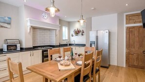 A modern kitchen with a wooden dining table, chairs, and a built-in oven. - 4 Market Cross House, Aldeburgh (Aldeburgh)