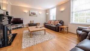 A living room with a fireplace, sofa, coffee table, and a large window. - 4 Market Cross House, Aldeburgh (Aldeburgh)