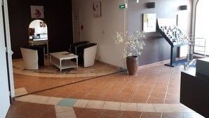 A lobby with a reception desk, seating area, and a staircase. - Appartement piscine (Mouans-Sartoux)