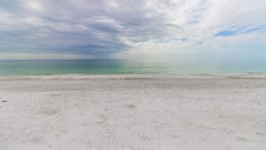 Une plage avec un rivage sablonneux et une mer calme sous un ciel nuageux.