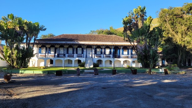 A colonial-style building with a tiled roof, multiple balconies, and a courtyard with tropical plants. - Hotel Fazenda Villa-Forte (Resende)