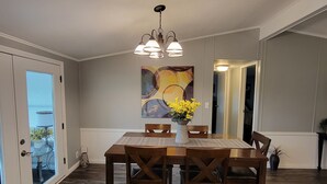 A dining area with a wooden table and chairs, a vase with flowers, and a painting on the wall. - Fishin' for Days! Waterfront Home with Covered Boat Dock in Okeechobee! (Okeechobee)
