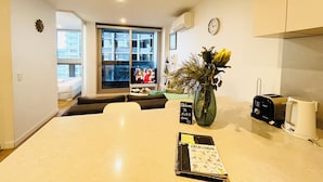 A modern kitchen with a large window, a dining table, and a vase of flowers.