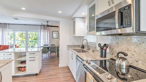 Una cocina moderna con electrodomésticos de acero inoxidable, encimera de granito y zona de comedor con vistas.