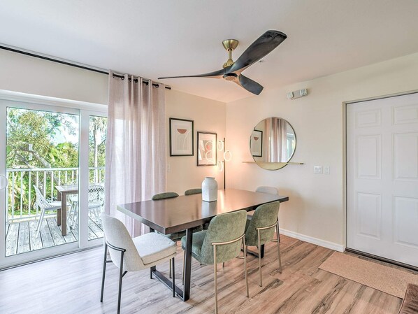 Un comedor con una mesa, sillas, un ventilador de techo y vistas al exterior.